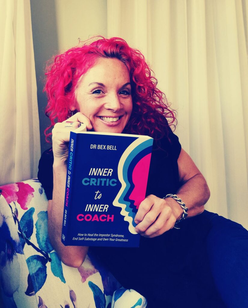 Dr Bex Bell holding her book Inner Critic to Inner Coach and smiling